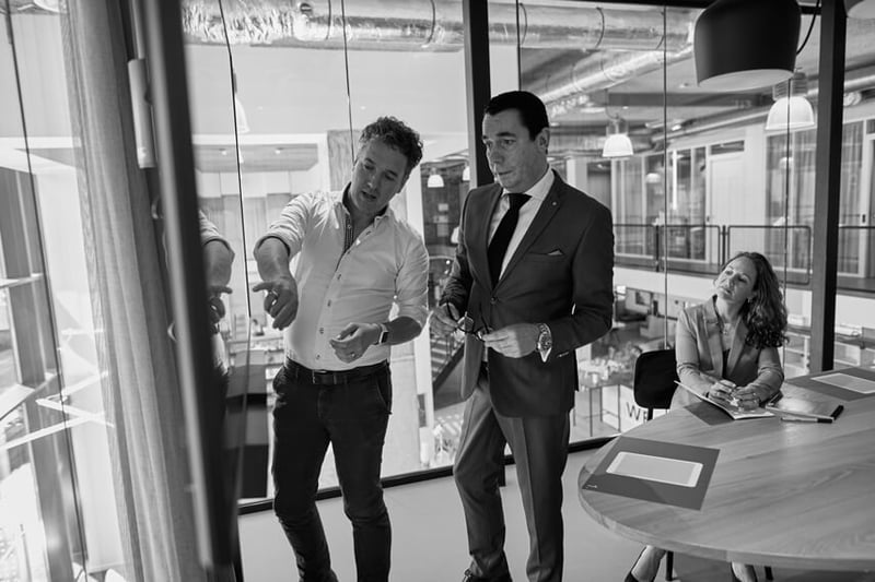 three people talking and pointing at whiteboard