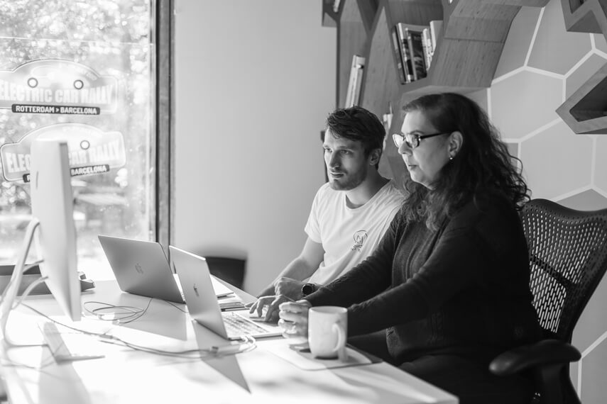 a man and a woman sitting at a table with a laptop.