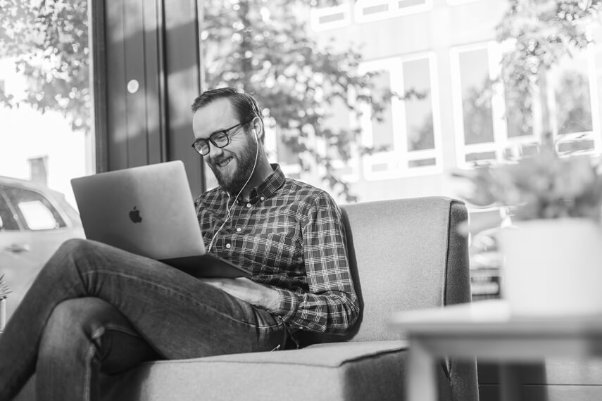 a man sitting on a couch using a laptop computer