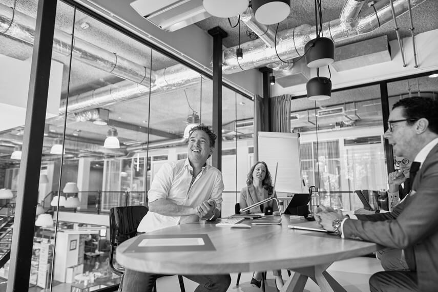 4 person around a table, meeting, laughing and looking up