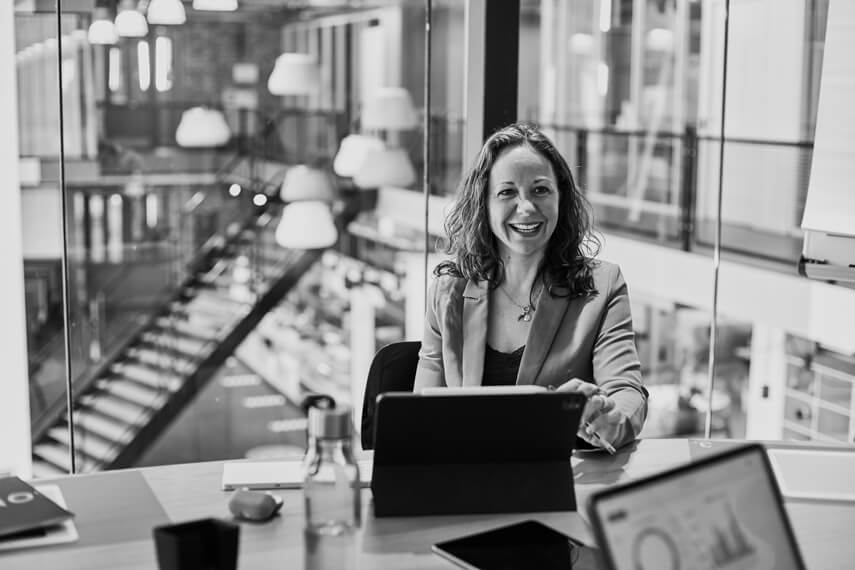 Woman behind laptop in a meeting, laughing.