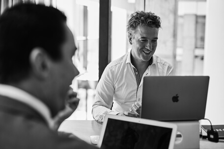 two men sitting at table with laptops