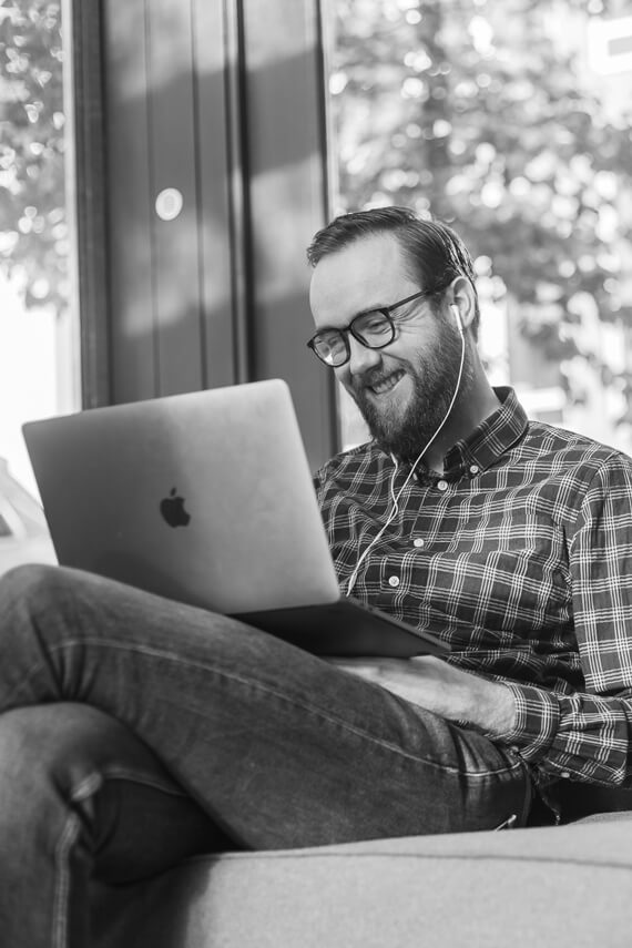 Guy with glasses sitting on couch with laptop on lap